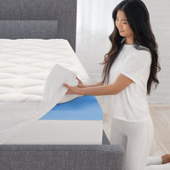 Young woman kneeling at the corner of the bed pulling the white fiberfill cover over the revealed corner of memory foam
