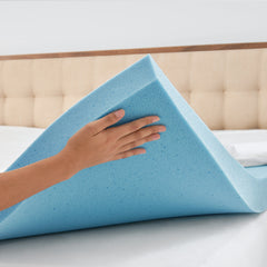 Woman's hand hoisting the front right corner of memory foam up off the mattress to reveal its breathable open cell design