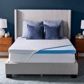 Novaform Advanced Cooling Mattress Topper placed on a mattress with the knit cover pulled back to reveal one corner of the gel memory foam topper. 