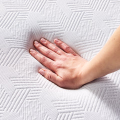 A woman’s hand presses down into the soft, hypoallergenic, cool-touch cover, showing its textured zigzag pattern. 