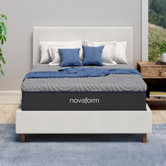 Front view of the Novaform Soothing Comfort 12 Inch Cooling Gel Memory Foam Mattress complete with white and royal blue pillows and a matching throw blanket
