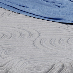 Close up view of the light gray quilted cover of the Novaform mattress with cooling fibers woven into the wave patterned design
