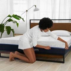 Young woman in pajamas kneeling by the Novaform mattress unzipping the SoFresh cover to wash it