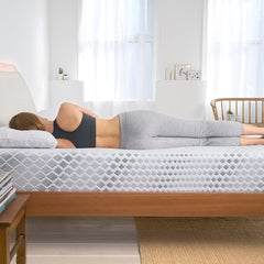 Young woman wearing athleisure lying on her side in bed with perfect spinal alignment