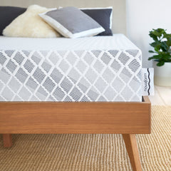 Corner front view of the mattress with  gray and white tailored cover showing a diamond pattern and a Novaform tag sticking out from the side