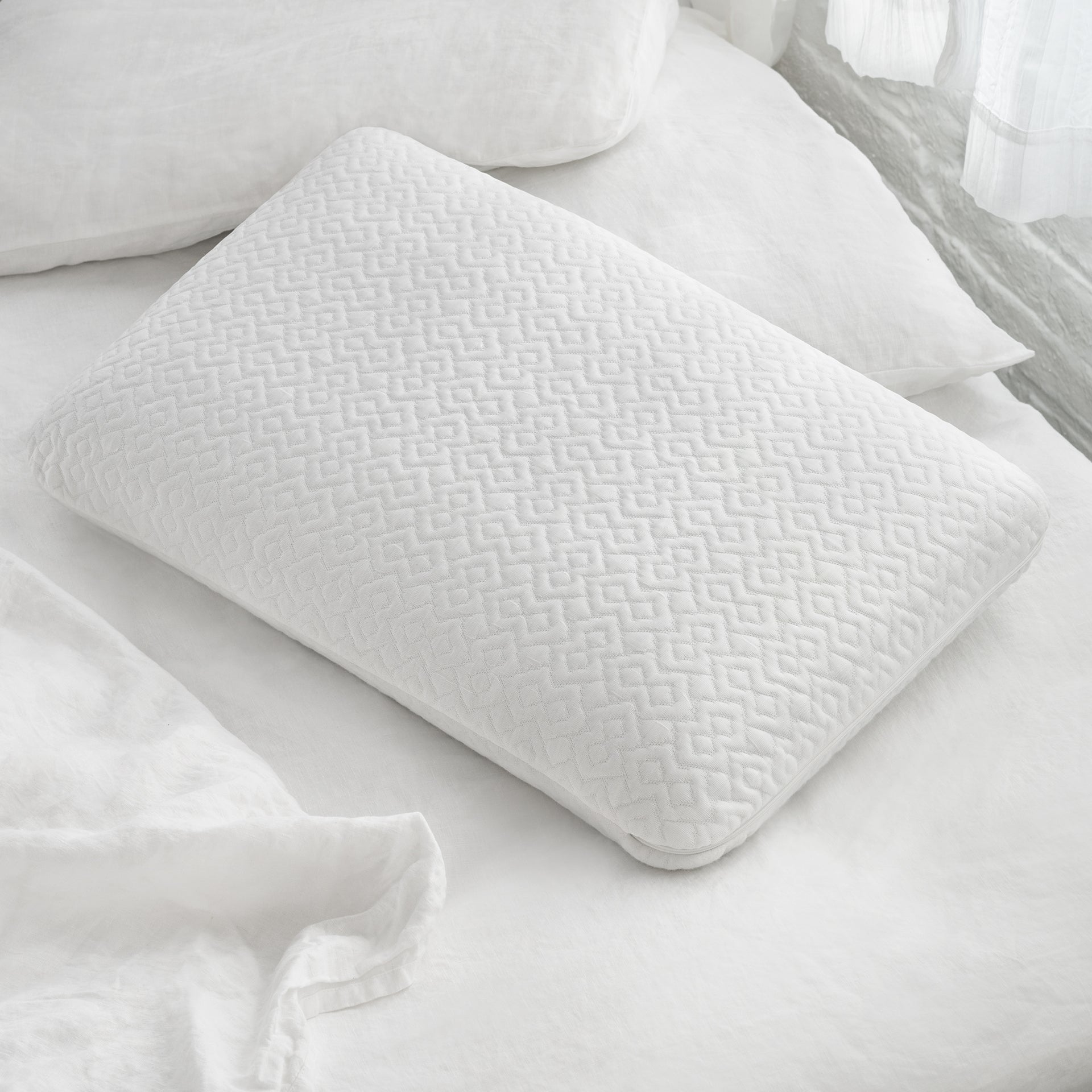The Novaform Lasting Cool Pillow resting on an unmade bed with white pillows and sheets around it