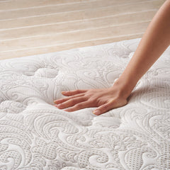 Woman's hand pressing down on the white and gray cover of the Serafina Pearl Mattress to show the mattress's responsive comfort