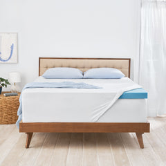 Front view of the Novaform ComfortLuxe Mattress Topper complete with baby blue pillows and a throw blanket