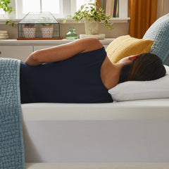 Woman wearing athleisure clothing lying on her side perfectly aligned in a bed complete with the Cool Drift foam topper